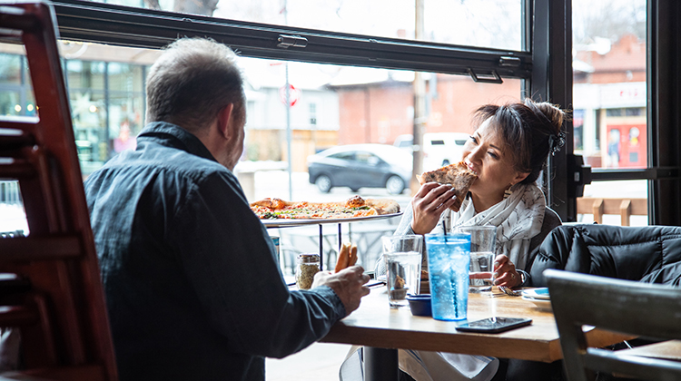 Man and woman eating pizza in pizzeria